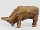 a wooden cow that is standing on a white surface