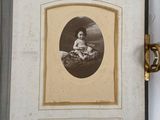 an old photo of a young boy sitting on a rock