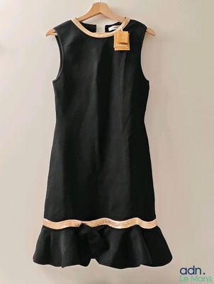 une robe noire accrochée au mur à côté d'un cintre en bois