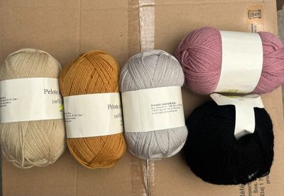trois pelotes de laine posées sur une boîte en carton