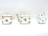 three teapots and a coffee pot sitting on a white surface