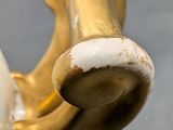 a close up of a gold and white vase on a table