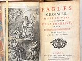 un vieux livre posé sur une table à côté d'une pile de livres