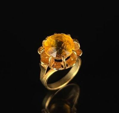 a close up of a gold ring with a yellow stone in it