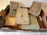 Plusieurs vieux livres se trouvent dans une boîte posée sur une surface blanche