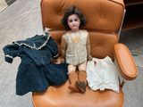 a doll that is sitting on a chair with clothes on it
