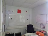 a whiteboard on the wall in an office with a black chair