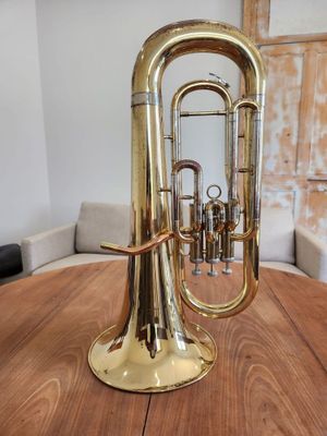 a brass trumpet sitting on a wooden table in a room