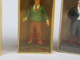 three plastic figurines of a man in a green jacket and a man in a green jacket