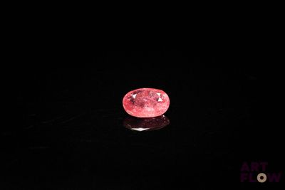 un diamant rose sur une surface noire dans l'obscurité