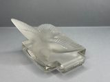 a glass bird sitting on top of a glass plate
