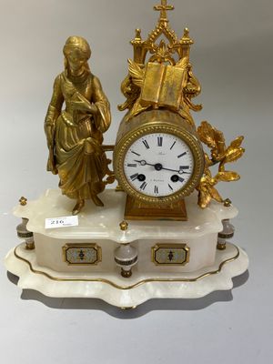 une horloge en or posée sur un socle en marbre