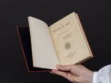 une personne tient un livre ouvert à la main sur un fond noir