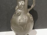 un vase en argent posé sur une table blanche