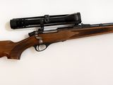 le fusil est posé sur une surface blanche, avec un pistolet dessus