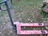 un chariot élévateur rouge posé au sol à côté d'un tas de bois