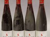 quatre bouteilles de vin sont alignées sur une surface blanche