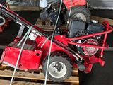 a small red tractor on a pallet in a garage