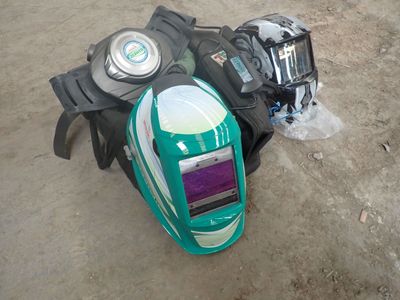 a green and white helmet sitting on the ground next to a backpack