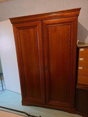 une photo d'une chambre à coucher avec un lit, une commode et une armoire