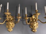 two gold wall sconces with white candles on a gray wall