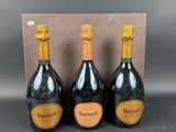 three bottles of champagne in front of a cardboard box