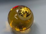 a yellow glass ball with a gold design on it