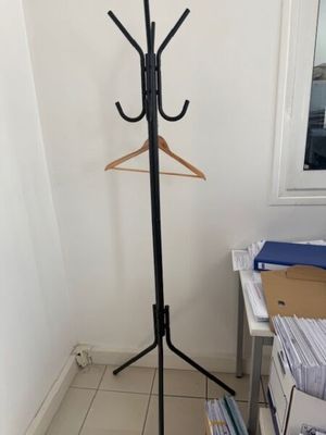 a coat rack with a coat hanger on it in the corner of a room