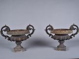 pair of antique bronze urns on pedestals on white background