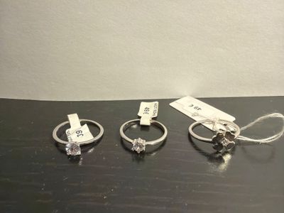 three silver rings with tags on them sitting on top of a table