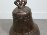an old bronze bell with a flower on top sitting on the floor