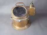 un casque de plongée ancien en laiton, doté d'un viseur noir, sur fond gris