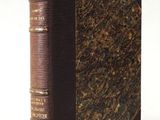 an old book with a brown cover sitting on top of a white surface