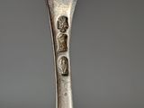 an old silver fork with a metal handle on a gray surface