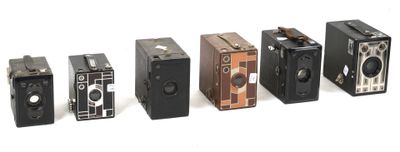 several old cameras are lined up in a row on a white surface