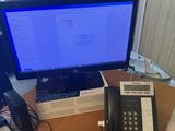 a desk with a phone, telephone, and a monitor on it