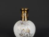 a white and gold vase sitting on top of a black table