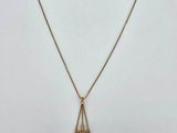 a gold necklace with a leaf pendant hanging from it ' s side
