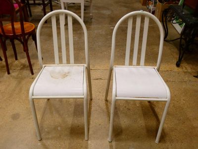 two white chairs sitting next to each other in a room