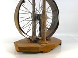 une petite maquette de rouet posée sur un socle en bois