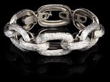 gros plan d'un bracelet en argent sur une surface noire