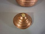 two copper pots sitting on a table next to each other