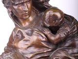 bronze statue of a woman holding a child on a marble base
