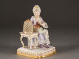 a figurine of a woman sitting on a chair