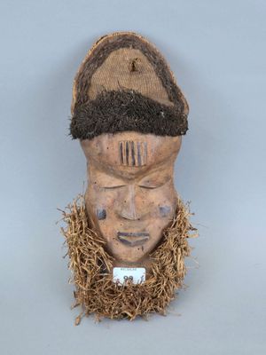 une image représentant un masque en bois surmonté d'un chapeau
