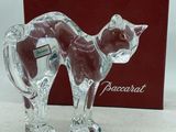 une figurine de chat en verre posée à côté d'une boîte rouge