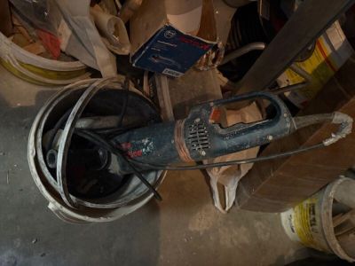 une image représentant une perceuse dans un seau posé par terre