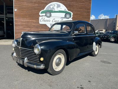 an old black car parked in front of a building