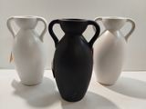 trois vases blancs et noirs posés sur une surface blanche