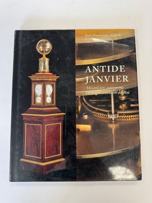 an antique janvier book with a clock on top of it